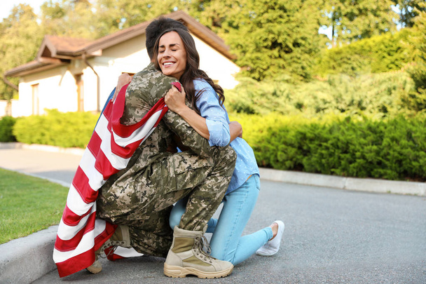 Man in military uniform with American flag hugging his wife outdoors - Photo, Image