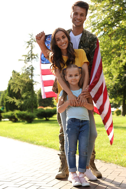 Man in military uniform with American flag and his family at sunny park - Fotó, kép