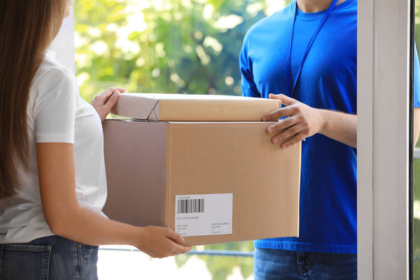 Woman receiving parcels from courier on doorstep, closeup - Foto, Imagem
