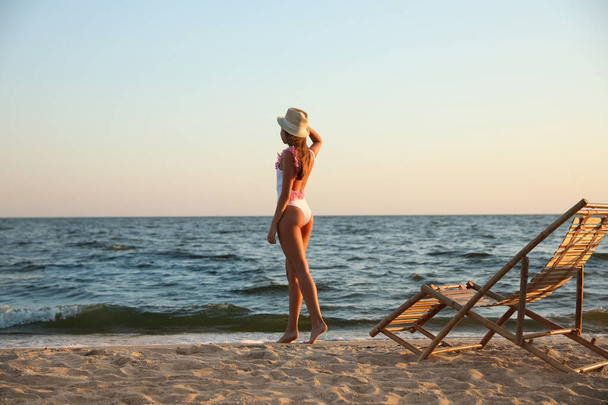 Young woman near deck chair on beach - Фото, изображение