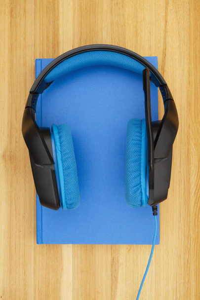 Auriculares azules y negros con micrófono y libro
 - Foto, Imagen