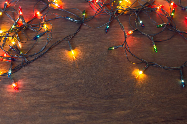 Luzes de Natal coloridas sobre fundo de madeira escura. Depósito plano
, - Foto, Imagem
