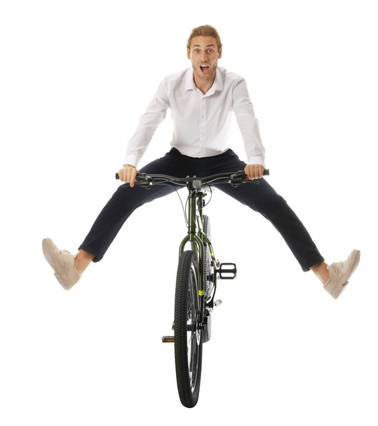 Excited young man riding bicycle on white background - 写真・画像