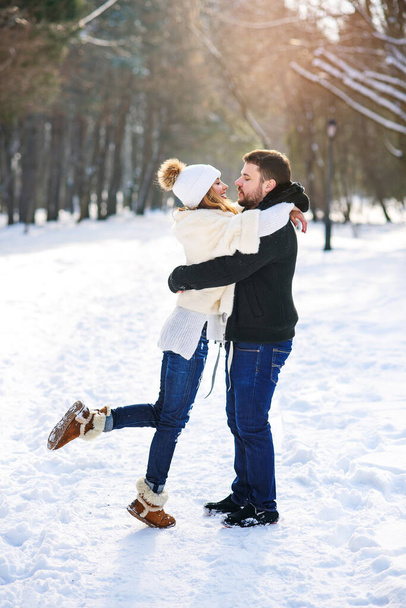 Beautiful couple in love hugging each other while walking in a winter Park. - Photo, image