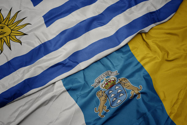acenando bandeira colorida de ilhas canárias e bandeira nacional de uruguai
. - Foto, Imagem