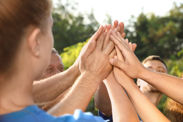 Група волонтерів, які об'єднують руки на свіжому повітрі в сонячний день
 - Фото, зображення
