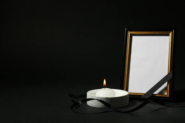 Funeral photo frame with ribbon and candle on black background. Space for design - Photo, image