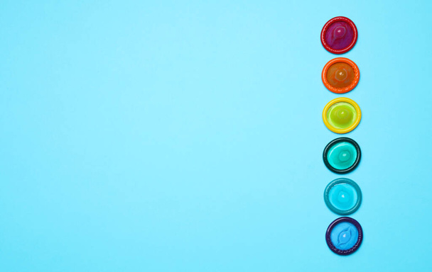 Colorful condoms on light blue background, flat lay. LGBT concept - Fotoğraf, Görsel
