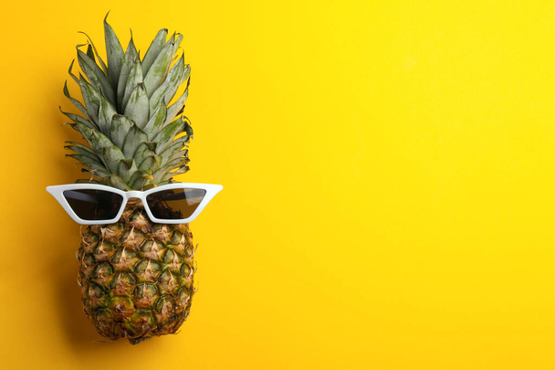 Pineapple with sunglasses on yellow background, top view. Space for text - Φωτογραφία, εικόνα