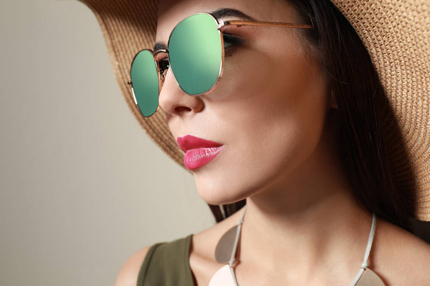 Beautiful woman in stylish sunglasses and hat on beige background - Fotoğraf, Görsel