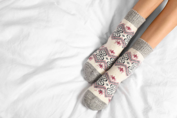 Woman wearing knitted socks on white fabric, top view with space for text. Warm clothes - Valokuva, kuva