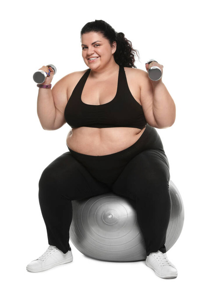 Overweight woman doing exercise on fit ball with dumbbells against white background - Foto, Bild