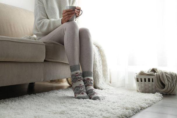 Woman wearing knitted socks at home, closeup. Warm clothes - 写真・画像