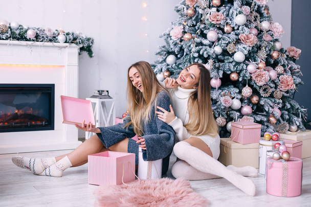 girls sit on the floor near the fireplace and Christmas tree and - Foto, afbeelding