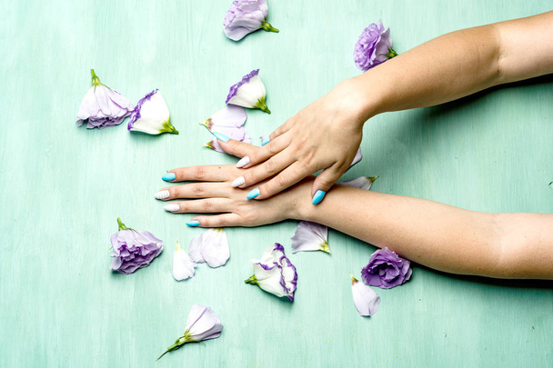 Hands of a woman with flowers on green background. - Photo, Image