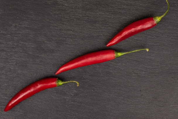 Red hot cayenne chili on grey stone - Foto, Bild