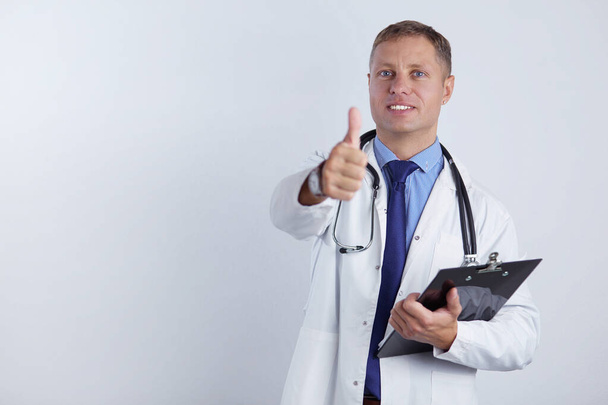 Portrait of handsome doctor in white coat holding a folder, showing Ok sign - Foto, Imagen