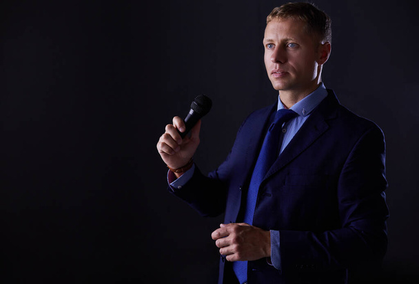 Portrait of a businessman standing with a microphone and looking ahead, speak at the conference - Foto, Imagen