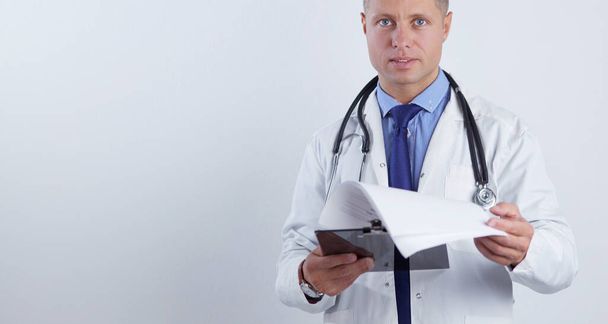 Male doctor standing with folder, isolated on white background - Fotoğraf, Görsel