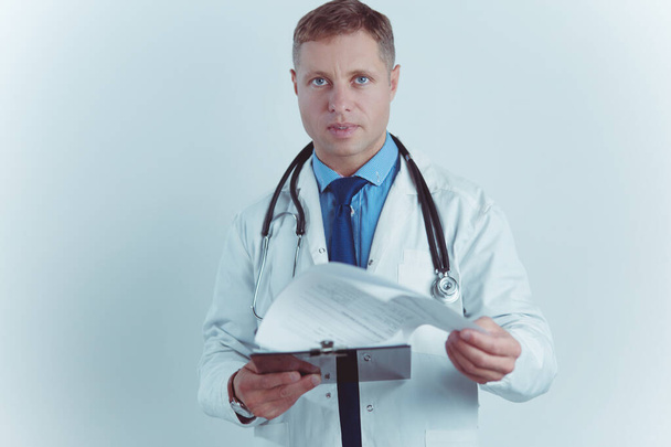 Médico varón de pie con carpeta, aislado sobre fondo blanco - Foto, imagen