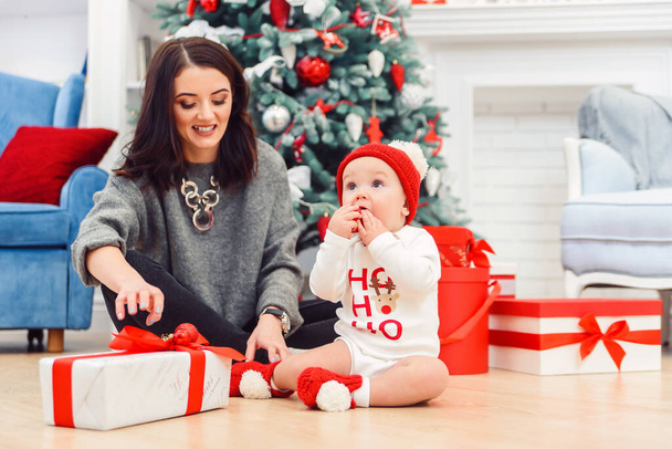 Charming toddler with her mother unpacking holidays gift. - Foto, imagen
