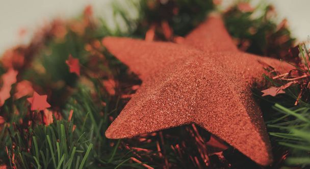 Yeşil ve kırmızı yaprakların üzerinde uzanan eski tarz Noel yıldızı - Fotoğraf, Görsel