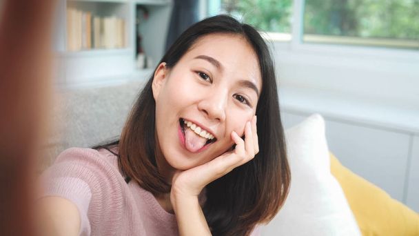 Jonge Aziatische tiener vrouw Vlog thuis, vrouw met behulp van smartphone maken Vlog video naar sociale media in de woonkamer. Lifestyle vrouw ontspannen in de ochtend thuis concept. - Foto, afbeelding
