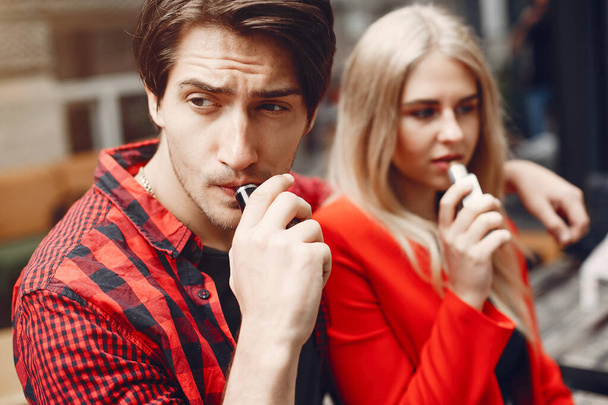 Stylish young couple with vape in a city - Фото, изображение