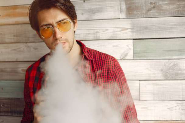 Stylish and elegant man in a city with vape - 写真・画像