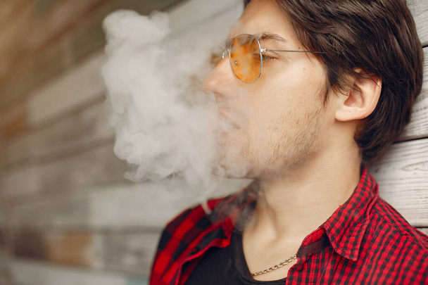 Stylish and elegant man in a city with vape - 写真・画像
