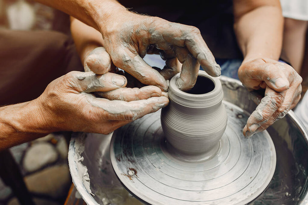 Grand-mère avec ses petits-enfants font des pichets en poterie
 - Photo, image