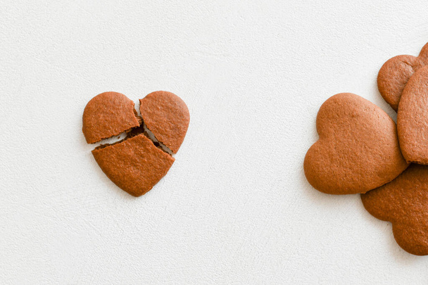 μπισκότα σε σχήμα καρδιάς, ένα από αυτά είναι σπασμένο σε λευκό φόντο. Ραγισμένα μπισκότα σε σχήμα καρδιάς ως έννοια ανεπιτυχών σχέσεων, ανεκπλήρωτη αγάπη. Έννοια του έρωτα χωρίς ανταπόκριση.. Ημέρα του Αγίου Βαλεντίνου ca - Φωτογραφία, εικόνα