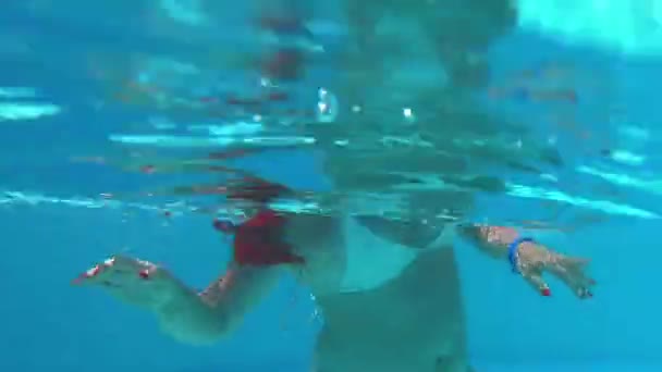 Μια μαυρισμένη γυναίκα κολυμπάει και βουτάει σε μια πισίνα σε ένα πάρκο με νεροτσουλήθρες. - Πλάνα, βίντεο