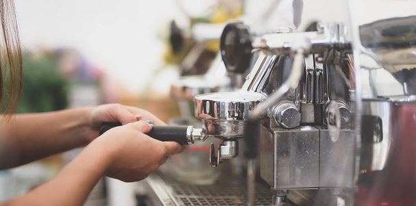 Female barista hand's grinding coffee with grinder machine - Photo, image