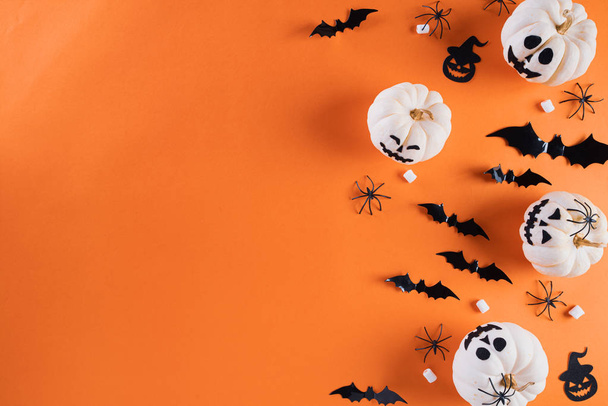 Top view of Halloween crafts, white pumpkin, ghost, bat and spider on orange background with copy space for text. halloween concept. - Фото, изображение