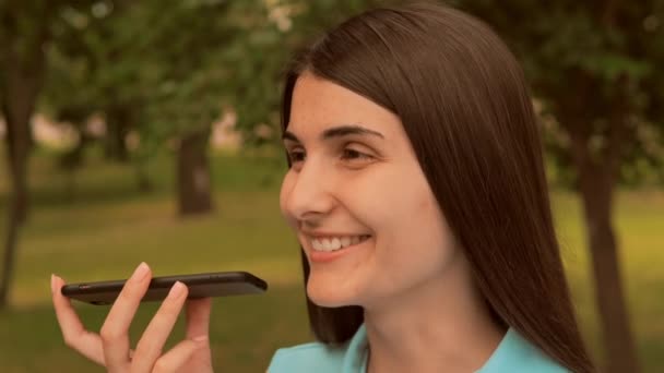 close up πρόσωπο χαρούμενα νεαρή γυναίκα μιλούν στείλει ηχητικό μήνυμα από το κινητό σε εξωτερικούς χώρους - Πλάνα, βίντεο