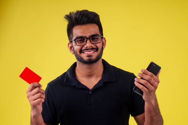 Young man holding business card in studio yellow background - Fotoğraf, Görsel