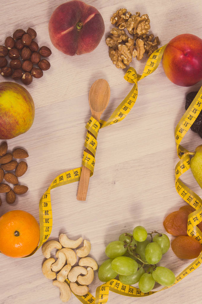 Puinen lusikka kääritty senttimetri ja hedelmät sisältävät luonnollisia vitamiineja, laihtumiseen, terveiden elämäntapojen ja ravitsemus käsite
 - Valokuva, kuva