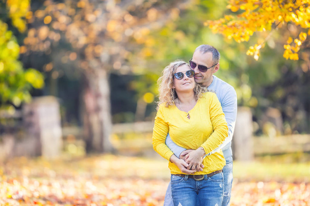 Happy mature couple in autumn park in the embrace - Fotó, kép