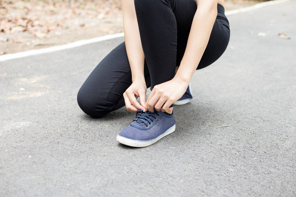 若い女性ランナーが靴ひもを結びスポーツの概念を - 写真・画像