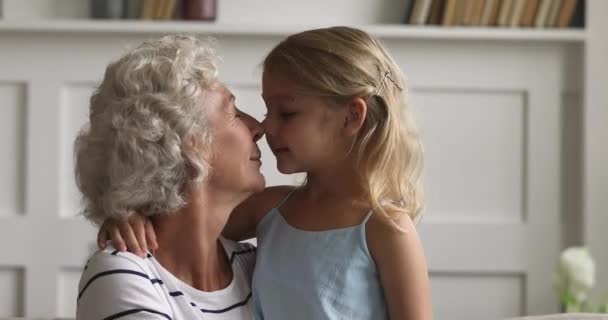 Happy old grandma embracing little granddaughter cuddling laughing at home - Materiał filmowy, wideo
