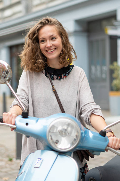 Sonriente y linda chica rubia posando en un scooter
 - Foto, Imagen