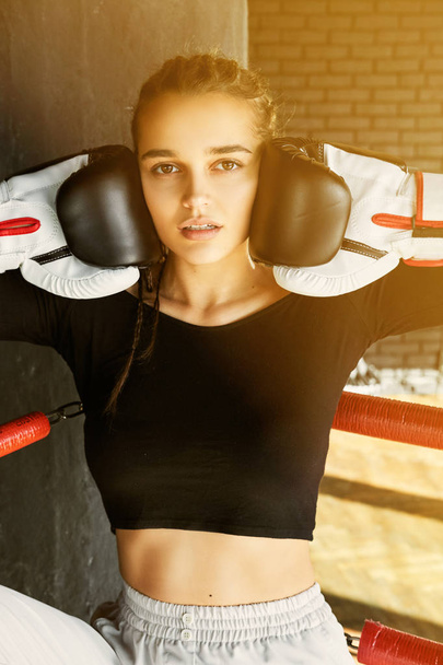 A young girl in boxing gloves stands in the ring. - Foto, afbeelding