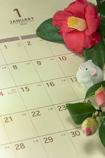 Ιαπωνική ευχετήρια κάρτα με λουλούδι Τσουμπάκι που ονομάζεται επίσης το τριαντάφυλλο του χειμώνα και χαριτωμένο ειδώλιο αρουραίου για το 2020 έτος του ποντικιού σε ένα ιαπωνικό ημερολόγιο ανοιχτό τον Ιανουάριο σελίδα. - Φωτογραφία, εικόνα