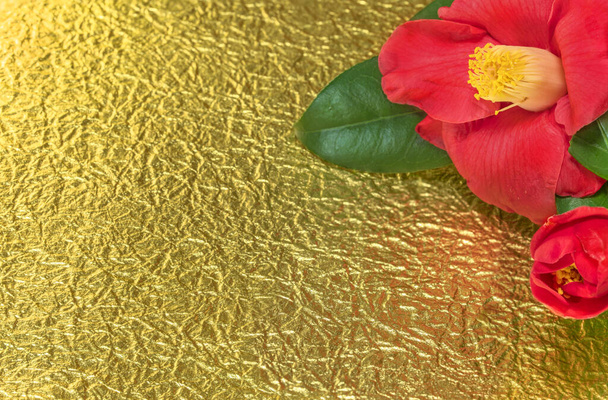 Una tarjeta de felicitación japonesa con una flor Tsubaki también llamada la rosa de invierno sobre un fondo de papel dorado arrugado
. - Foto, imagen