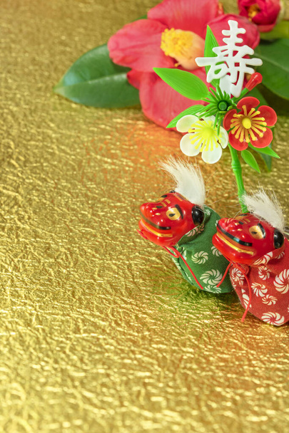 A Japanese greeting card with a Tsubaki flower also called the winter rose and two adorables Japanese Folklore animals figurines depicting Shishimai lions with an ornament decorated with the Japanese Kotobuki ideogram which means longevity - Photo, Image