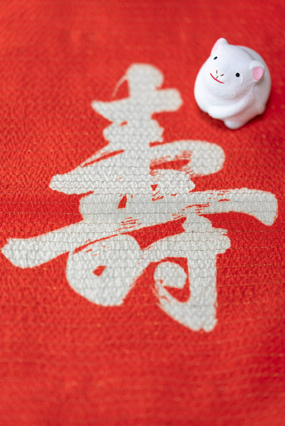 Японская открытка с красивой крысиной фигуркой в 2020 году на красной ткани, украшенной японской идеографией Котобуки, что означает долголетие
. - Фото, изображение
