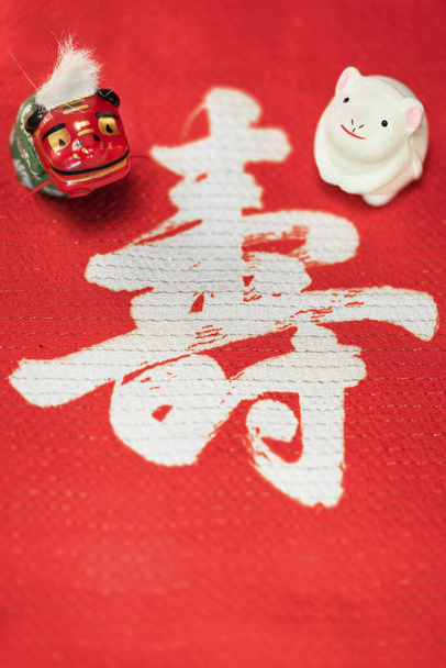 Une carte de vœux japonaise avec une jolie figurine de rat pour l'année 2020 de la souris et une figurine animale folklorique représentant un lion Shishimai sur un tissu rouge décoré de l'idéographe japonais Kotobuki ce qui signifie longévité
. - Photo, image