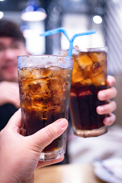Young couple with glasses of refreshing cola with ice in restaurant, Two glasses of cola with ice - Photo, Image