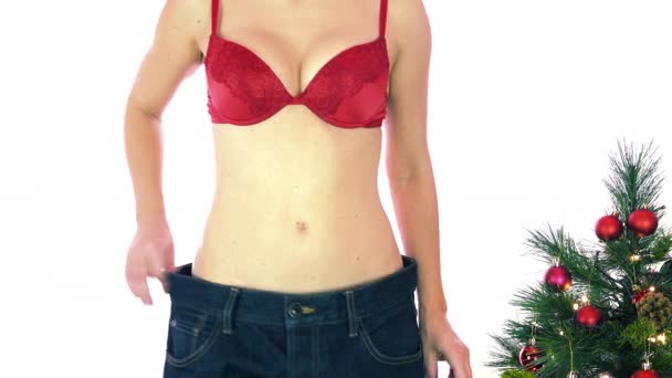 Hubená žena v červené podprsence ukazuje velké kalhoty, léky a doplňky. Koncepce diety s prášky a tabletami, hubnutí a tělesná kontrola, přibývání tuku a štíhlé dolů během vánočních svátků - Záběry, video